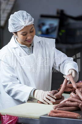 Female butcher processing sausages