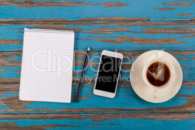 Notepad, pencil, smartphone and cup of tea