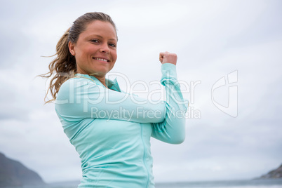 Portrait of woman performing stretching exercise on beach