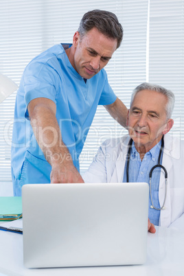 Surgeon and doctor discussing over laptop