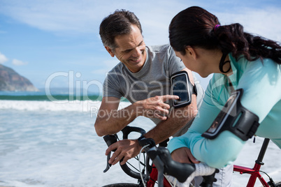 Couple leaning on bicycle while using mobile phone