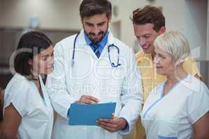 Doctor and nurse having discussion over file in corridor
