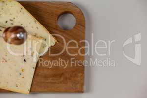 Knife on cheese slice on wooden board