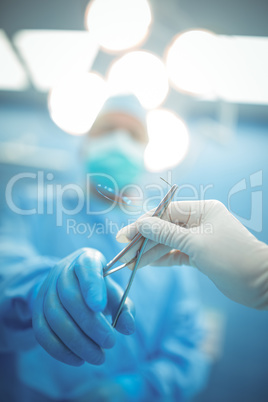 Surgeon passing surgical tool to colleague in operation theater
