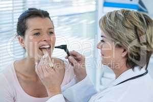 Doctor examining patients teeth with otoscope
