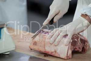 Butcher cutting meat at meat factory