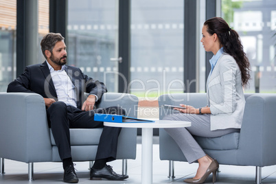 Businessman sitting on armchair and talking with colleague