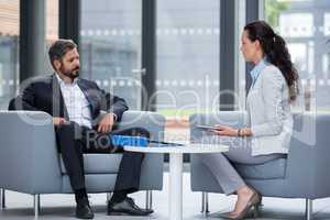 Businessman sitting on armchair and talking with colleague