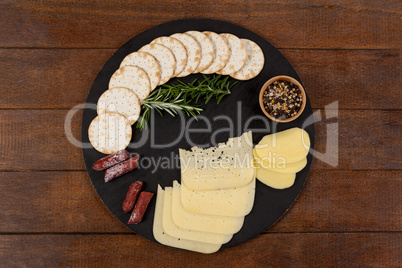 Cheese, rosemary, sausages, spices, biscuits and potatoes on slate board