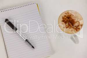 Cup of coffee with spiral notepad and pen