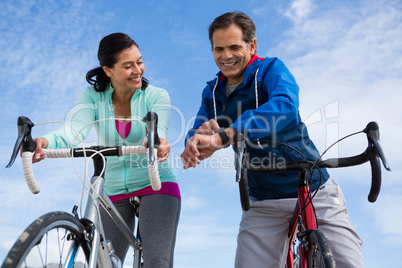 Couple leaning on bicycle while interacting with each other