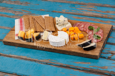 Cheese with ham and crispy biscuits on chopping board