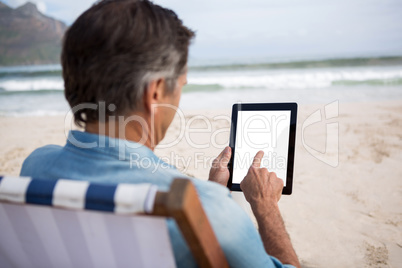 Rear view of man using digital tablet on beach