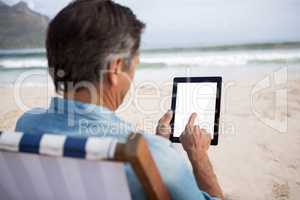 Rear view of man using digital tablet on beach