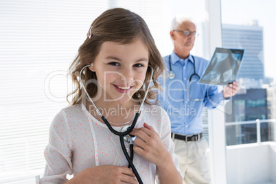 Girl checking her own heartbeat using a stethoscope