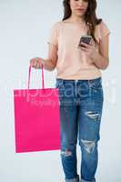 Woman carrying shopping bag and using mobile phone