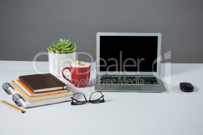 Laptop, mouse, cup of coffee with notebooks