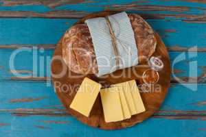 Bread loaf with slices of cheese and sauce on wooden serving board