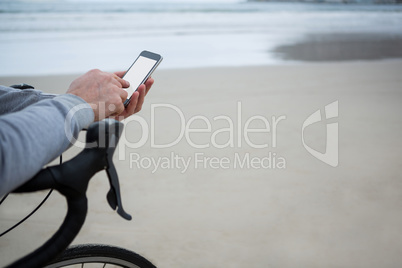 Close-up of man hand on bicycle using mobile phone