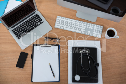 Computer, laptop, smart phone, clipboard, pen, spectacles, stethoscope and cup of coffee
