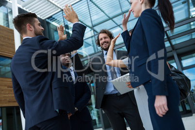 Group of happy businesspeople giving high five to each other