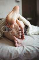 Couple showing their feet while lying on a bed