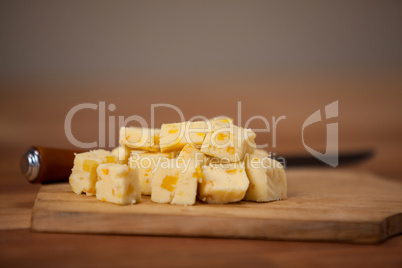 Cheese cubes on wooden chopping board