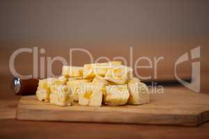 Cheese cubes on wooden chopping board