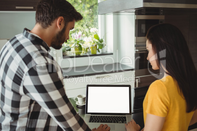 Couple using laptop in the kitchen