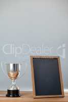 Trophy and chalkboard on wooden table