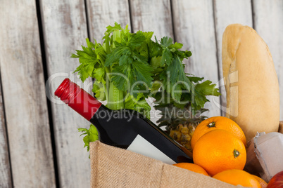 Wine bottle, fruits and vegetables with bread loaf in grocery bag