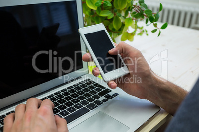 Graphic designer using mobile phone at his desk