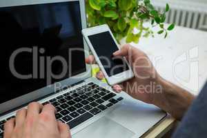 Graphic designer using mobile phone at his desk