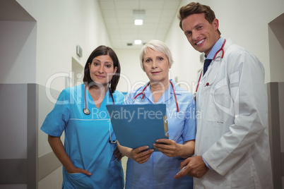 Team of doctors having discussion over file in corridor