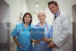 Team of doctors having discussion over file in corridor