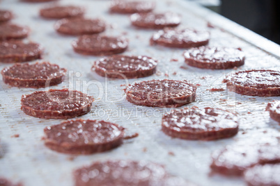 Raw meat patties on assembly line
