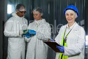 Technician writing on clipboard at meat factory