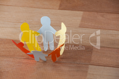 Multicolored paper cut outs forming a circle on wooden background