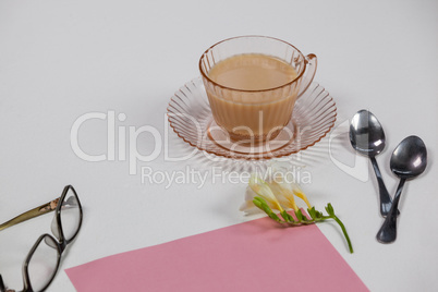 Cup of tea, spoons, blank page, spectacles, paper balls and flower