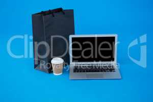 Shopping bag and disposable coffee cup with laptop