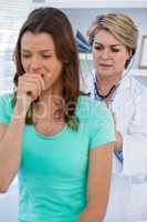 Doctor examining coughing patient with stethoscope