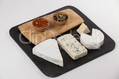 Sliced cheese, bowls of jam and spices on chopping board