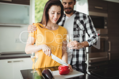 Happy couple chopping vegetables in kitchen