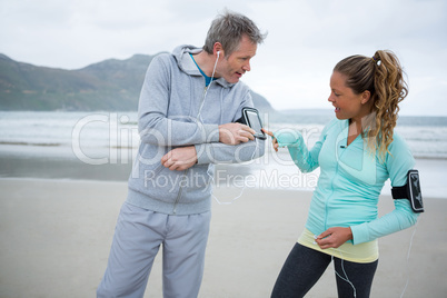 Couple using mobile phone while listening music on beach