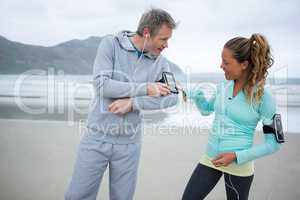 Couple using mobile phone while listening music on beach