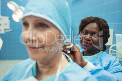 Female surgeon helping her co-worker in wearing surgical cap