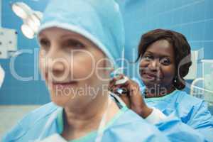 Female surgeon helping her co-worker in wearing surgical cap