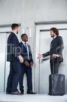 Businessmen talking while waiting for elevator