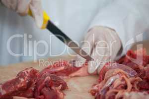 Butcher cutting meat at meat factory