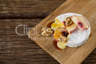 Brie cheese, with apricot and walnut pieces on serving board